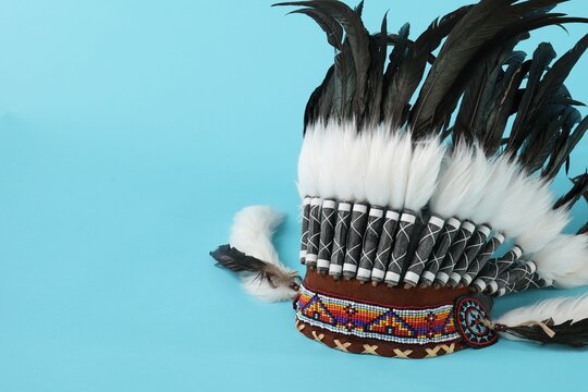 Traditional warbonnet (Native American chief headdress) on light blue background, space for text