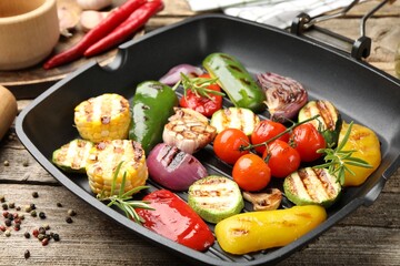 Pan with grilled vegetables and spices on wooden table, closeup