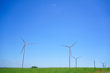 Fototapeta premium Wind turbines generating renewable energy under clear blue sky, symbol of sustainability, clean power, green technology, and environmental conservation for a better future.
