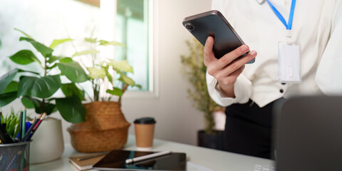 Mobile Communication. Woman holding smartphone in modern office.