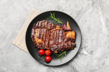 Delicious grilled beef steak with rosemary, onion and tomatoes on grey textured table, top view