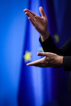 Deaf mute person gestures during a press conference with European Union flag in background
