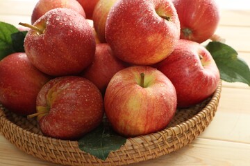 Fresh apples and green leaves on wooden table, closeup