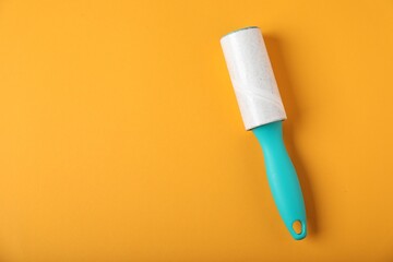 One lint roller on orange background, top view. Space for text