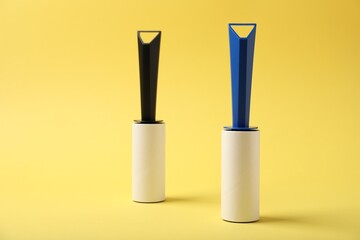 Two sticky lint rollers on yellow background