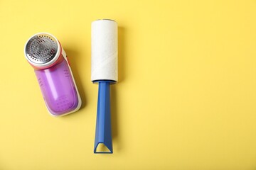 Lint roller and fabric shaver on yellow background, flat lay. Space for text