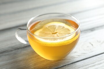 Aromatic tea with lemon in cup on wooden table, closeup