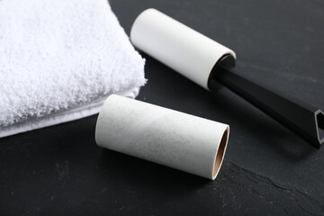 Lint roller, adhesive roll and towel on black table, closeup