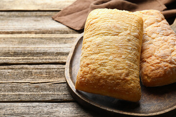 Fresh crispy ciabattas on wooden table, closeup. Space for text