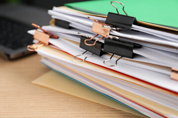 Many folders with documents and laptop on wooden desk, closeup