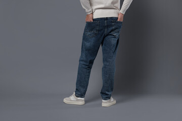 Naklejka premium Man in stylish jeans on grey background, closeup