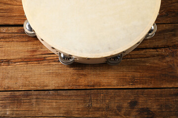 Tambourine on wooden background, closeup. Space for text