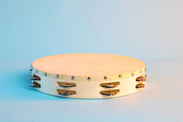 Tambourine on light blue background, space for text