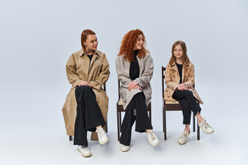 Obraz premium Three generations of red haired women share a moment in stylish autumn outfits