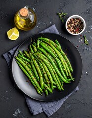 Roasted green beans on a dark plate, garnished with chili flakes