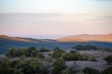 Obraz premium a view of rolling hills and dry grassland under a softly clouded sky,