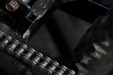 Closeup of motorcycle chain and sprocket. metal part of gear drive transmission system during maintenance, with powerful and gritty industrial feeling