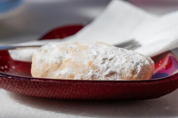 a sugar-dusted pastry sits invitingly on a vibrant red glass plate