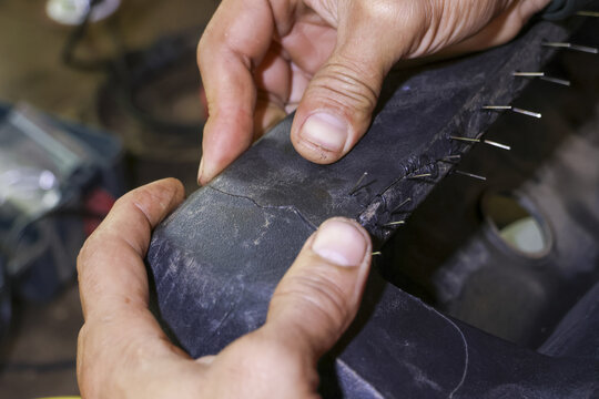 Focused mechanic hand doing repair work on plastic car bumper. This auto welding service in garage shows detailed process of fixing cracked vehicle part