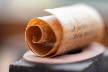 Kleine Papierrolle aus einer sehr alten Buchseite mit altdeutscher Schrift. Als Makro fotografiert.