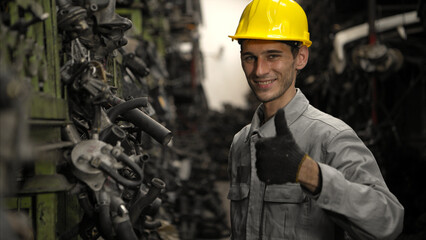 Fototapeta premium Portrait of factory worker wearing a safety helmet inspecting used car parts