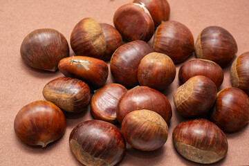 Fresh chestnuts on brown background. Natural autumn harvest concept, organic seasonal food