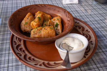 Stuffed cabbage leaves, cabbage rolls, and dolma in a clay pot, served with sour cream. Cabbage wraps. Chow Farsi, dolma, sarma, cabbage rolls, or golabki. Flat lay, arrangement, overhead.
