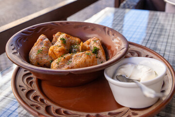 Stuffed cabbage leaves, cabbage rolls, and dolma in a clay pot, served with sour cream. Cabbage wraps. Chow Farsi, dolma, sarma, cabbage rolls, or golabki. Flat lay, arrangement, overhead.