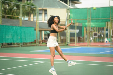 Obraz premium Energetic African Woman Playing Tennis Outdoors