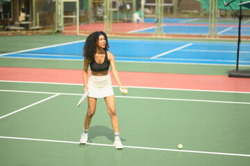 Fototapeta premium African female tennis player preparing to serve the ball on an outdoor court, showing focus, confidence, and athletic strength