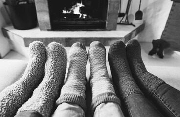 Legs view of happy family wearing warm socks in front of fireplace - Winter, love and cozy concept - Focus on center socks - Black and white editing