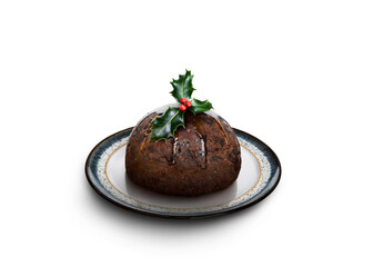 Looking down on a round patterned plate with a traditional Christmas pudding and sprig of holly on top isolated against a transparent background.