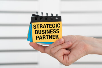 A person is holding a stack of sticky notes with the words Strategic Business Partner on them