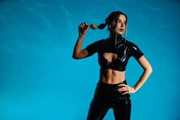 Captivating model in stylish black latex outfit strikes a pose in studio setting