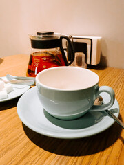 Coffee and tea setup in a cozy caf&eacute; at morning time with elegant cups and utensils on a wooden table