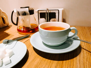 Warm tea served in a light blue cup on a wooden table at a cozy cafe