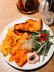 Cozy cafe breakfast of salmon, scrambled eggs, and fresh veggies. Delicious!