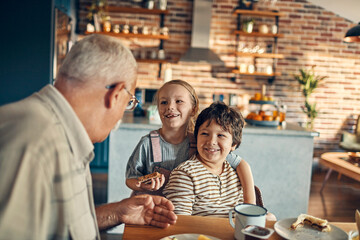 Grandfather enjoying breakfast with grandchildren at home