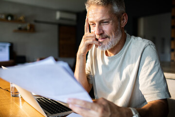 Mature man reviewing bills and finances at home