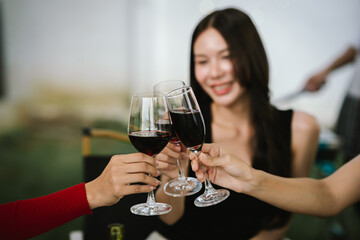 Happy young friends celebrate together at a stylish restaurant, enjoying wine, laughter, and friendship during an elegant evening gathering.	