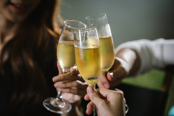 Happy young friends celebrate together at a stylish restaurant, enjoying wine, laughter, and friendship during an elegant evening gathering.	