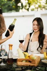 A woman smiling and toasting with a glass of wine during an evening celebration, surrounded by soft bokeh lights and a warm atmosphere.