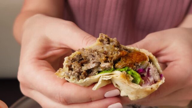 Spicy doner kebab or shawarma in hands, with fried meat, fresh salad and vegetables with sauce. High quality 4k footage