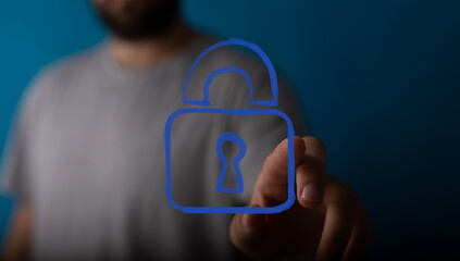 A man's hand touches a glowing blue digital padlock icon, symbolizing cybersecurity, data...