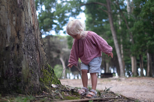 Blonde girl found a mushroom in the forest and pokes it with a stick