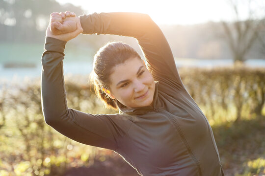 Young sporty woman is stretching after workout, training and running on a beautiful winter morning	
