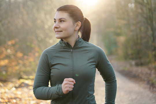 Sporty girl in sportswear jogging, running and training outdoors on a early winter morning	