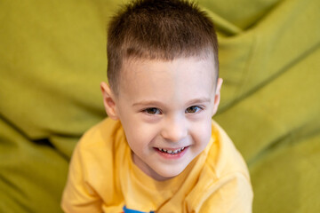 Happy toddler boy 3 or 4 years old smiles while looking at the camera indoor. Childhood and lifestyle concept. Portrait photo, close-up © Andrii Yalanskyi