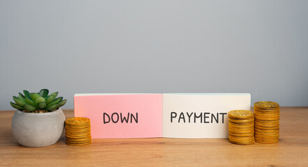 Down payment concept. Initial upfront payment made when buying a house, car, or expensive item, reducing the amount that must be financed or borrowed. Notebook with inscription and coins