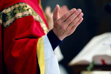 Fototapeta premium Sunday mass in a catholic parish. Priest praying at eucharist celebration. Close up on hands. Bonneville. France.